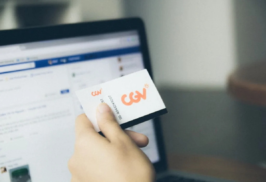 Person holding a business card in front of a laptop