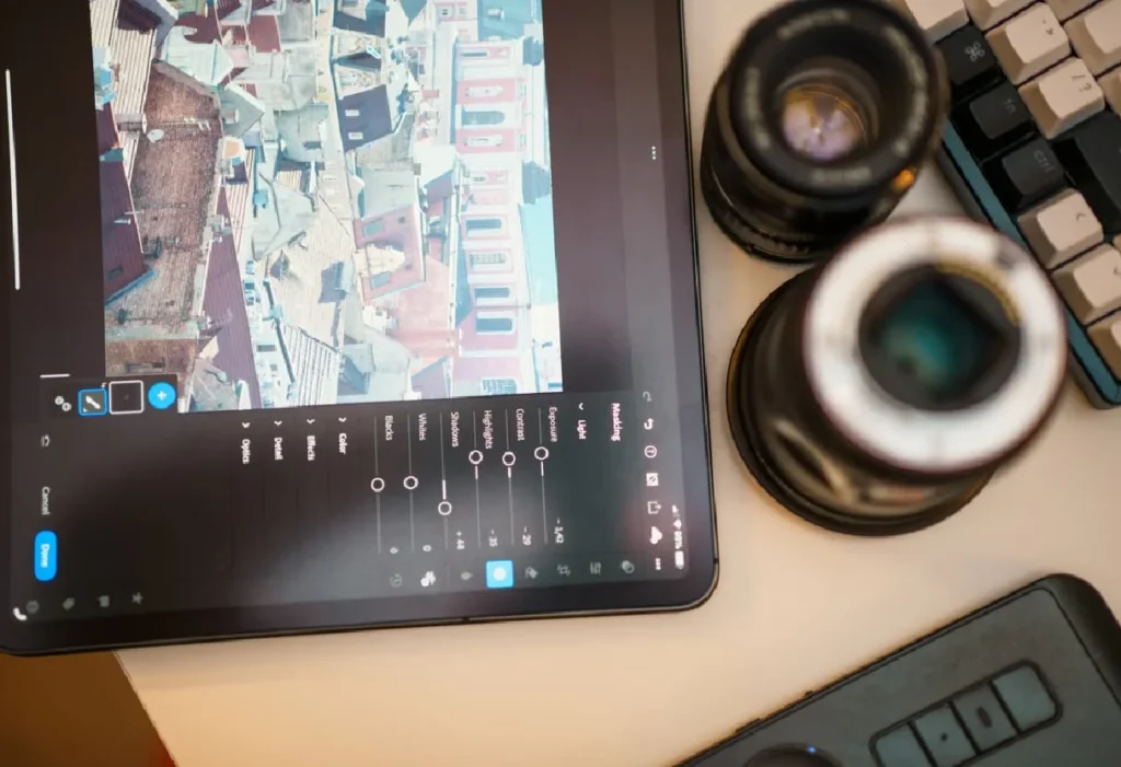 Photo editing on a tablet beside camera lenses
